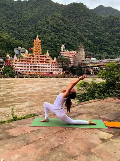 Laura in un affondo con il braccio teso verso l'alto, sulla riva del Gange a Rishikesh