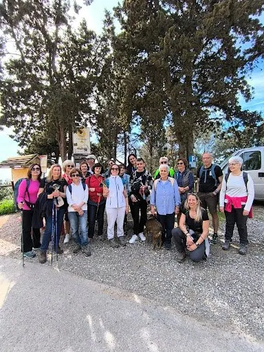 Il gruppo pronto a partire, con zaini e bastoncini, sotto i pini