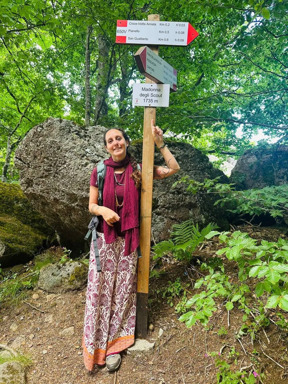 Laura Buoncristiani sorridente accanto ai cartelli dei sentieri, nel bosco dell'Amiata