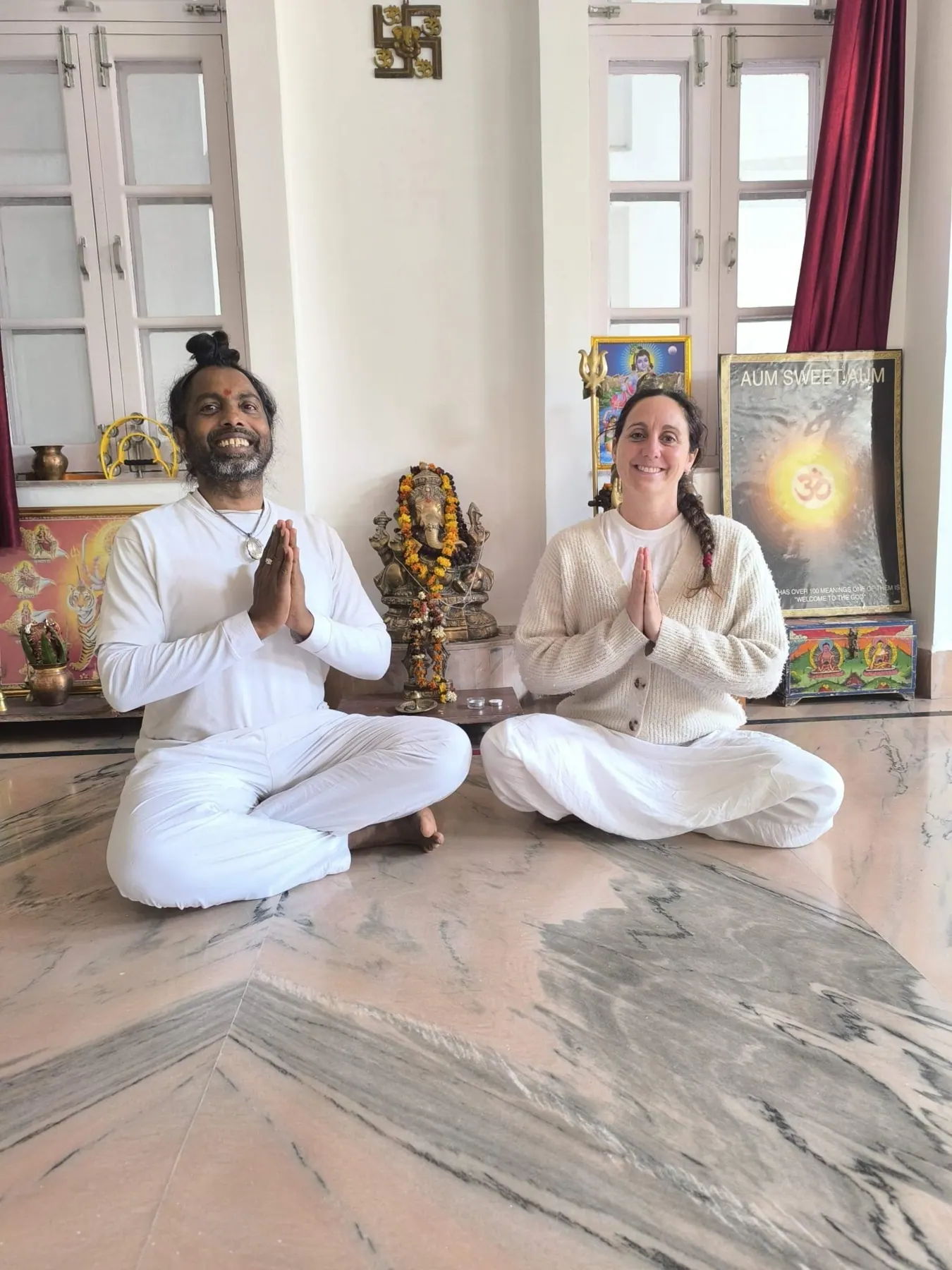 Laura Buoncristiani e il Dr. Jitendra Das seduti a gambe incrociate e a mani giunte nella sala di pratica, in India