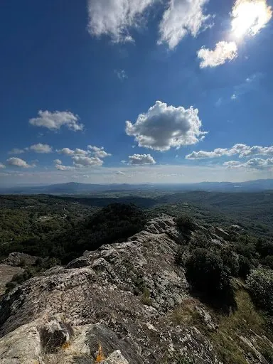 I massi di riolite in cima, con la vista sulle colline e un cielo di nuvole bianche