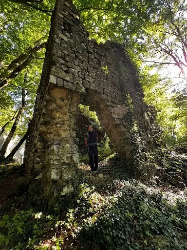 Le mura in rovina della Rocca degli Aldobrandeschi avvolte dal verde, con una persona sotto l'arco