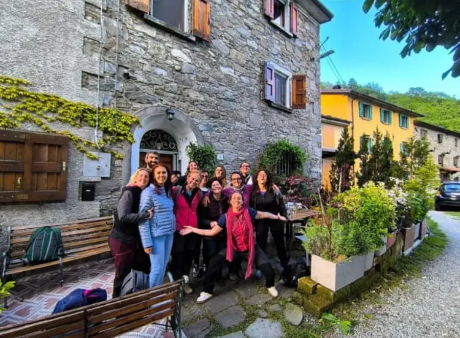 Il gruppo sorridente davanti a una casa di pietra del paese