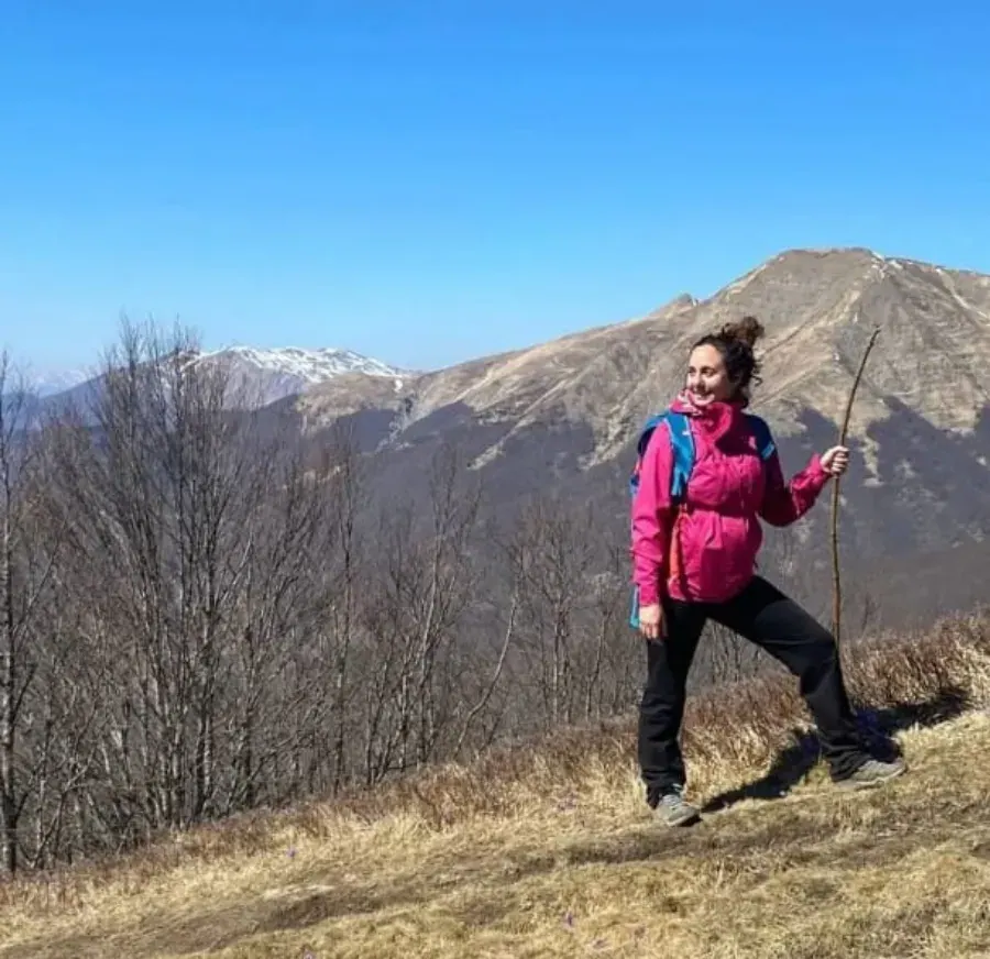 Una camminatrice sul crinale, con i monti innevati alle spalle