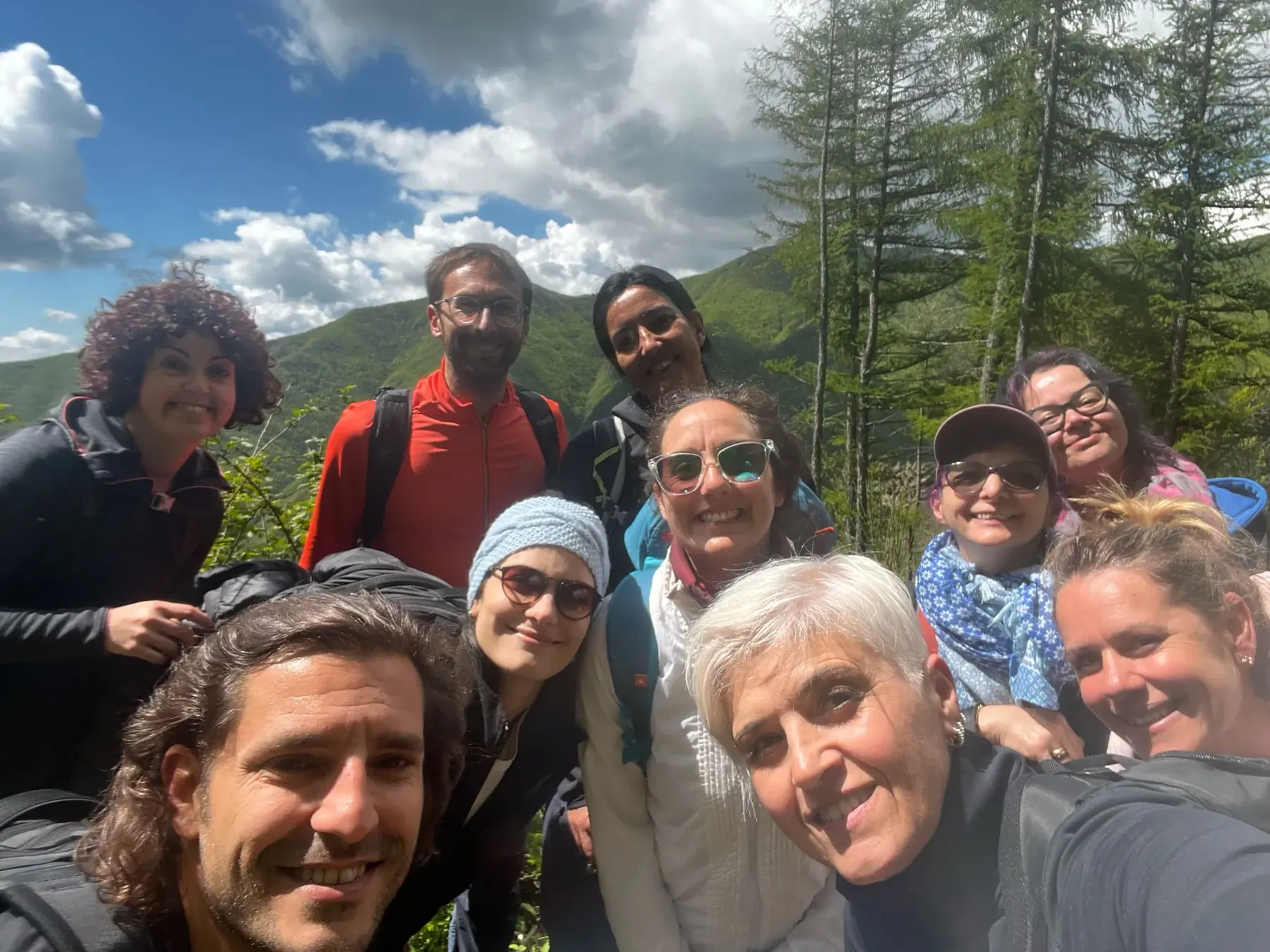 Un selfie del gruppo sorridente con i monti e il cielo alle spalle