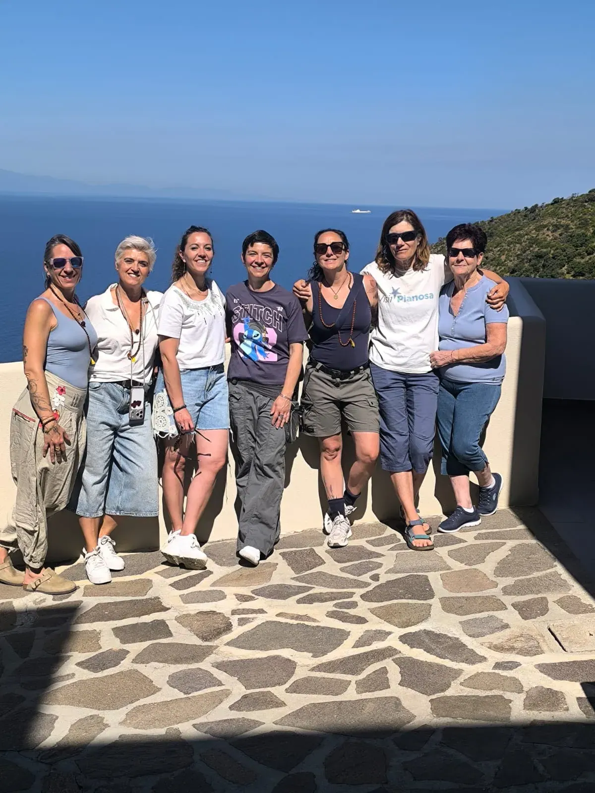 Il gruppo abbracciato su una terrazza in pietra sopra il mare
