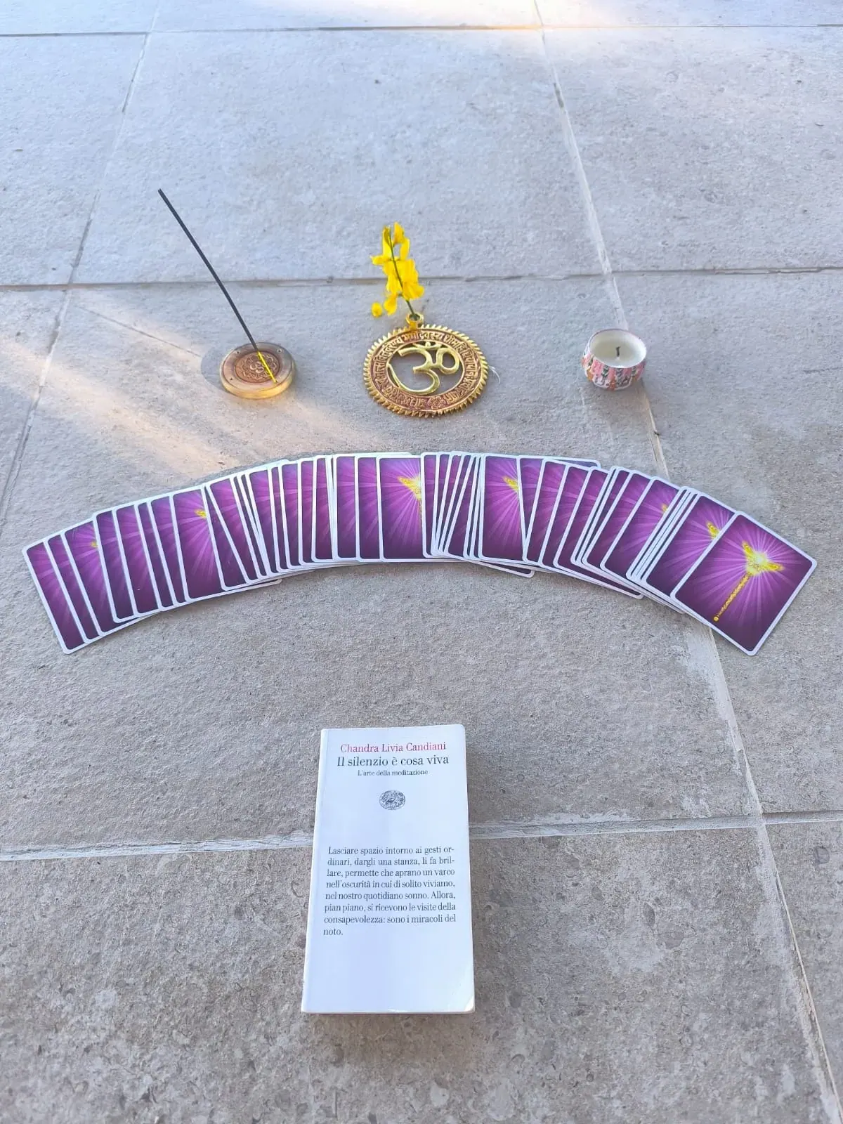 Un ventaglio di carte viola sul pavimento, con l'incenso e un biglietto di riflessione
