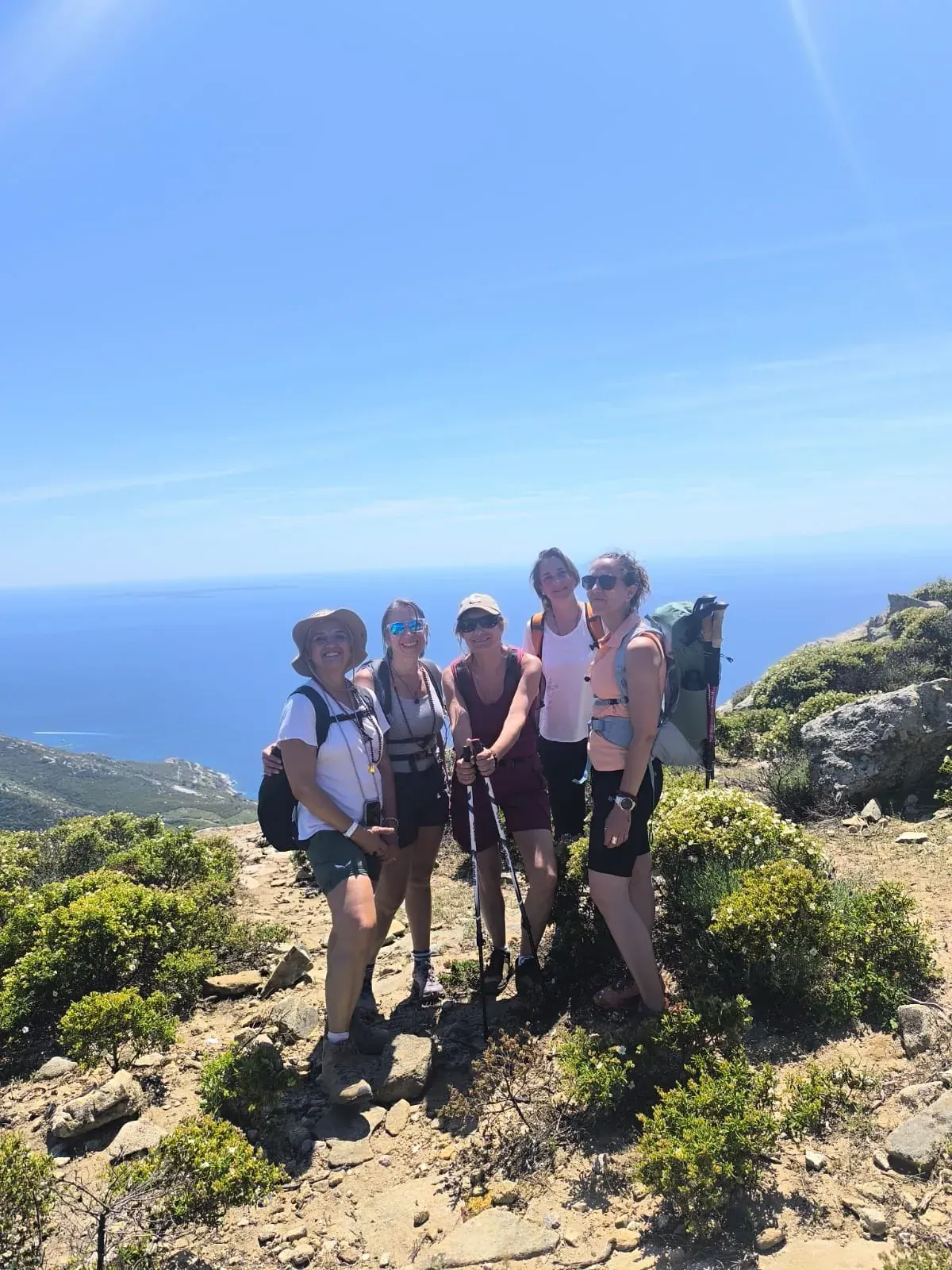 Il gruppo in cima a un sentiero fra le rocce e la macchia, con il mare sullo sfondo