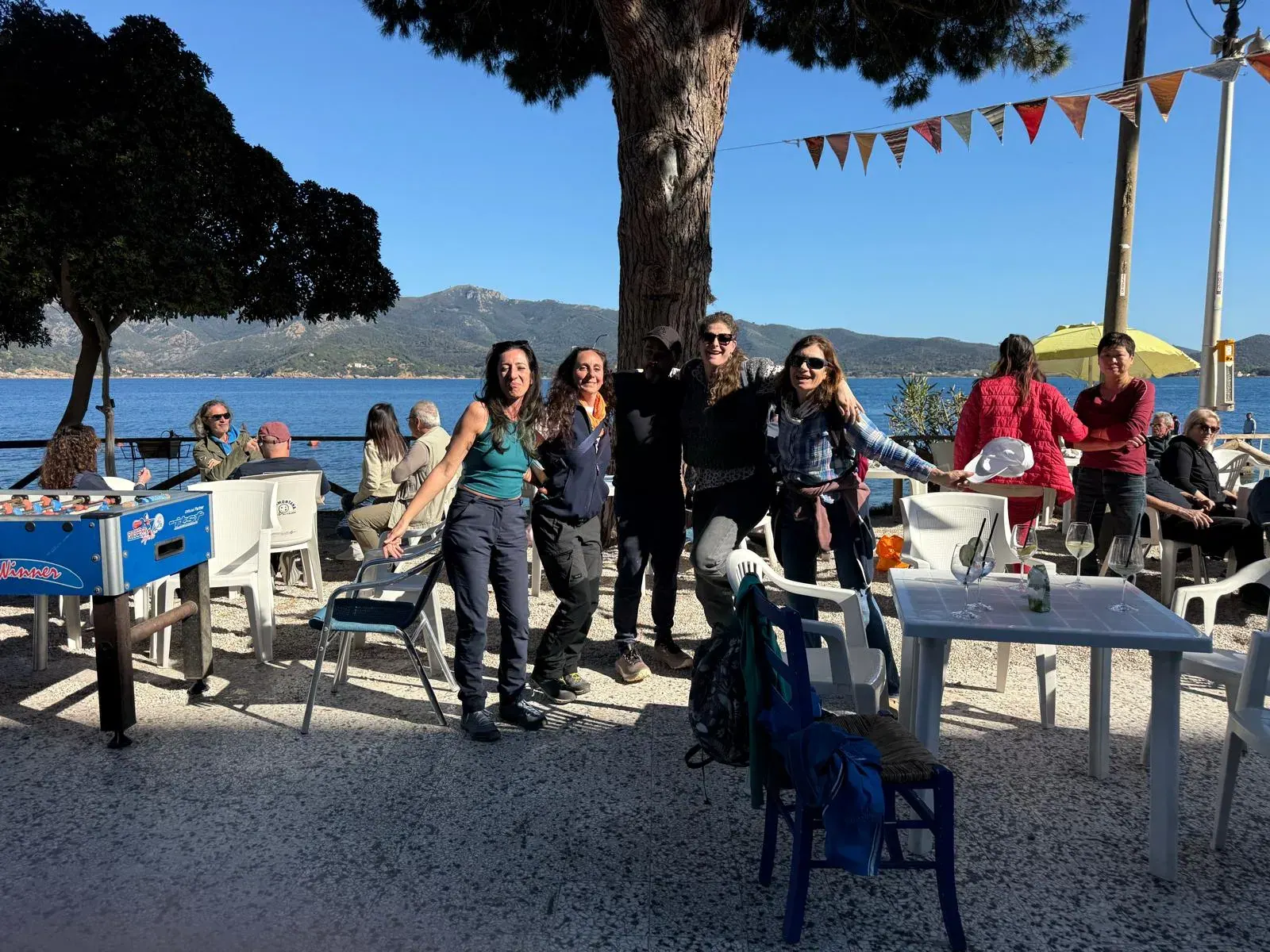 Il gruppo festeggia in un bar sul lungomare, sotto le bandierine
