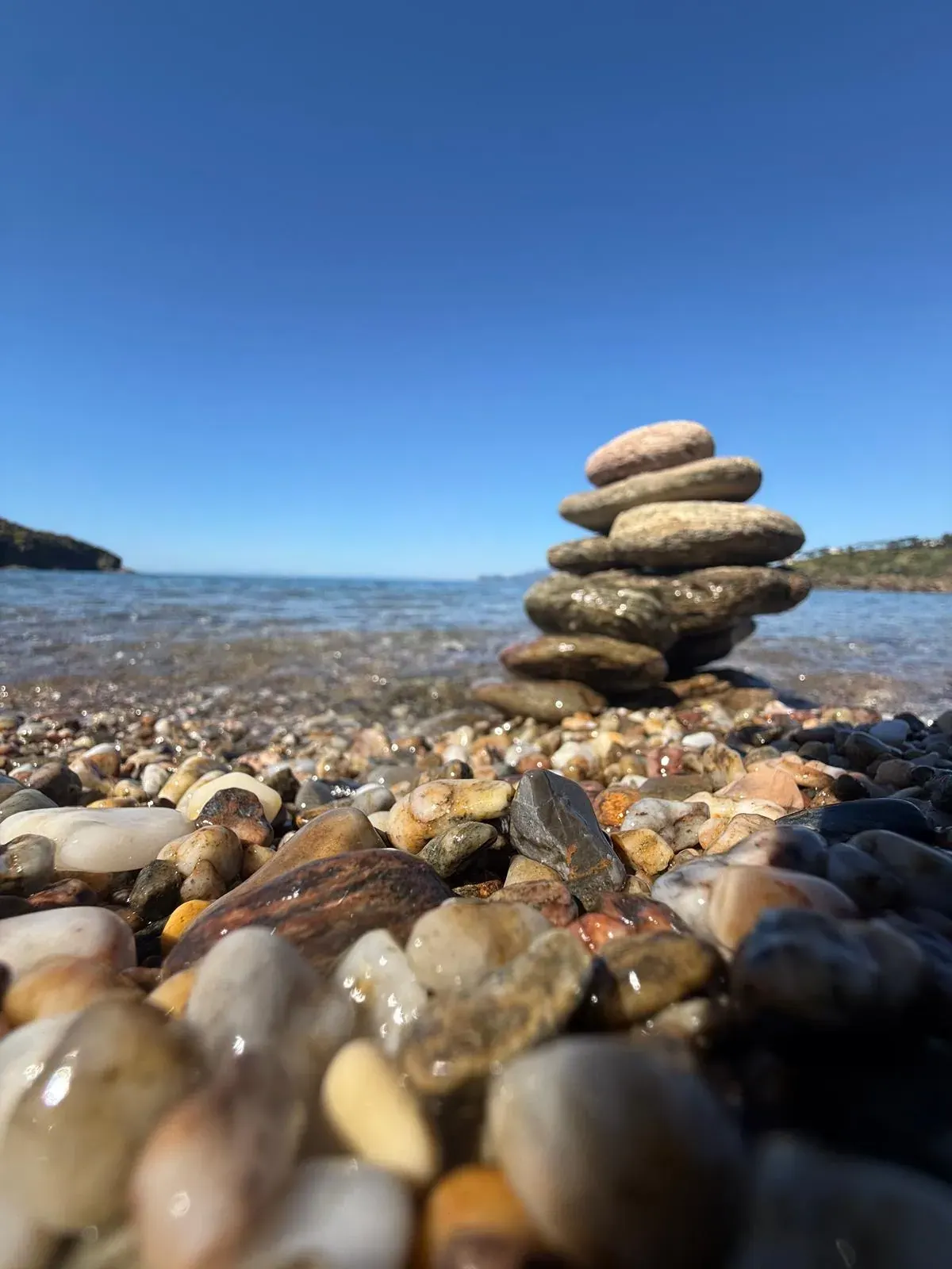 Una piccola torre di sassi sulla spiaggia di ciottoli, davanti al mare